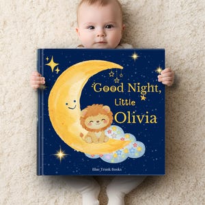 Può includere: Un libro per bambini blu navy con il titolo "Good Night, Little Olivia" in lettere dorate. La copertina presenta una luna crescente gialla sorridente, un leone dei cartoni animati e stelle. Il libro è tenuto da un bambino.