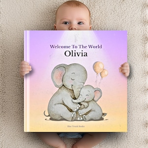 Puede incluir: Un libro para bebés personalizado titulado "Welcome To The World Olivia" con una ilustración de dos elefantes grises abrazándose. Dos globos flotan en el fondo. El libro tiene un fondo degradado púrpura y amarillo y lo sostiene un bebé.