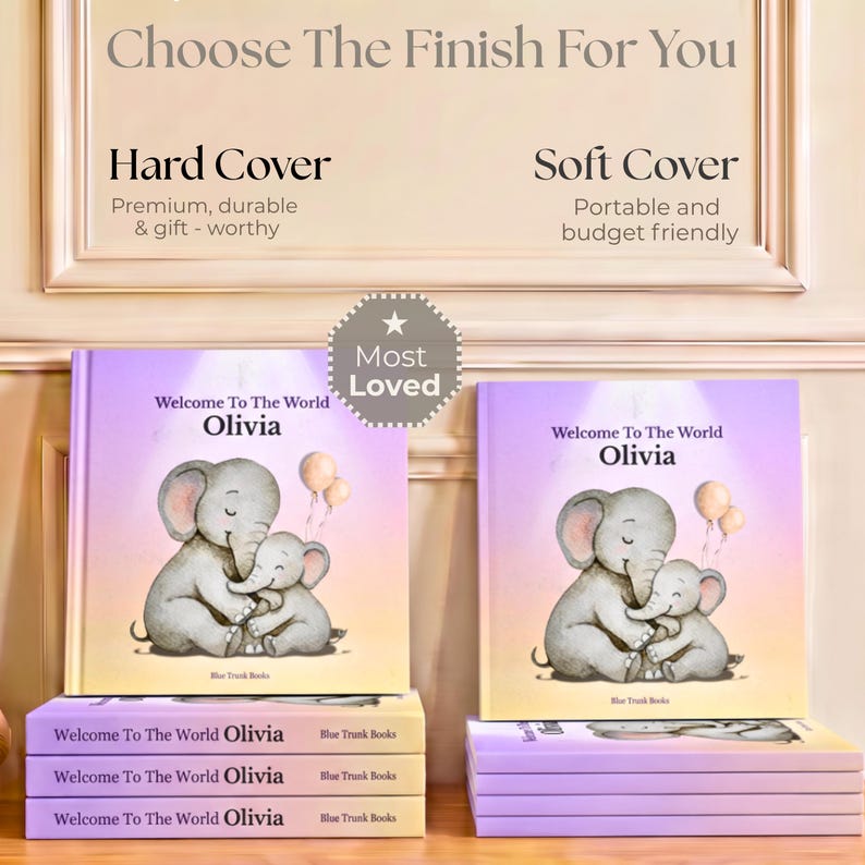 K&ouml;nnte beinhalten: Zwei Kinderb&uuml;cher mit dem Titel Welcome To The World Olivia und einer Illustration von zwei Elefanten. Der Text Choose The Finish For You, Hard Cover und Soft Cover ist sichtbar. Ein Abzeichen mit dem Text Most Loved ist mittig platziert.