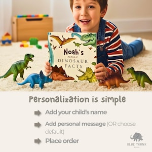 Puede incluir: Un libro de tapa dura titulado Noah's Big Book of Dinosaur Facts con ilustraciones de dinosaurios en la portada, rodeado por cuatro figuras de dinosaurios de pl&aacute;stico en colores verde, azul y marr&oacute;n sobre una superficie texturizada.
