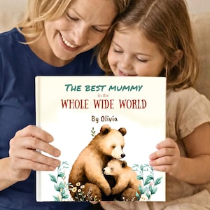 Op de afbeelding: Een vierkant hardcover boek met de titel The Best Mummy in the Whole Wide World by Olivia. De kaft bevat een aquarelillustratie van een grote bruine beer die een kleine welp knuffelt, omringd door groene planten en kleine gele bloemen.