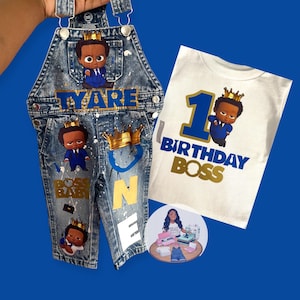 Könnte beinhalten: Jeans-Latzhose und ein weißes T-Shirt mit dem Thema "Boss Baby". Die Latzhose ist mit Farbspritzern, dem Namen "TYARE" und "BOSS BABY" Grafiken verziert. Das T-Shirt trägt die Aufschrift "1st Birthday Boss".