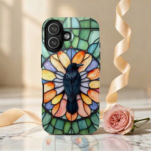 May include: A rectangular smartphone case featuring a central black raven illustration set against a vibrant, multi-colored stained glass pattern. The design incorporates shades of orange, purple, blue, and green, with a camera cutout at the top left.