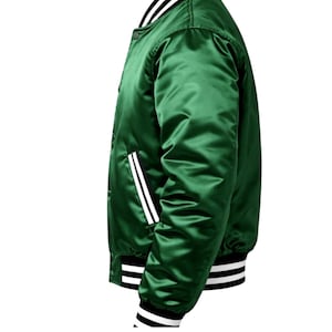 Puede incluir: Chaqueta bomber de sat&eacute;n verde vibrante. La chaqueta presenta rayas blancas en los pu&ntilde;os, el cuello y los bolsillos, con un acento de raya negra. Tiene una parte delantera abotonada y una silueta bomber cl&aacute;sica.