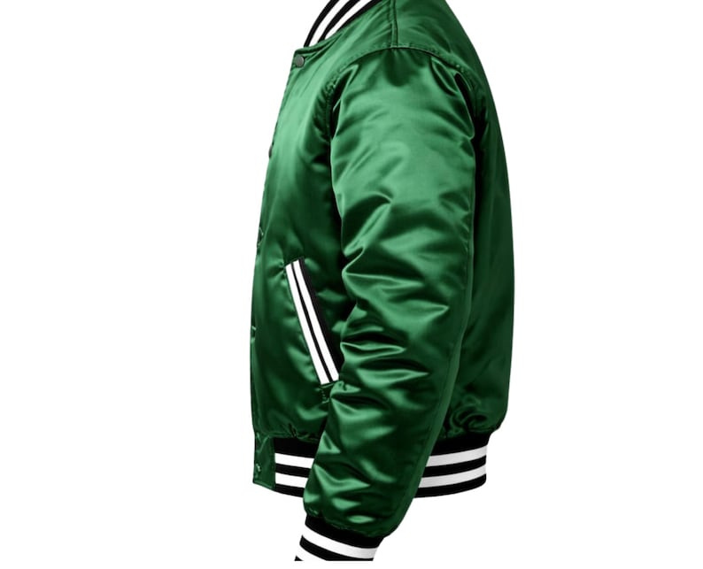 Puede incluir: Chaqueta bomber de sat&eacute;n verde vibrante. La chaqueta presenta rayas blancas en los pu&ntilde;os, el cuello y los bolsillos, con un acento de raya negra. Tiene una parte delantera abotonada y una silueta bomber cl&aacute;sica.