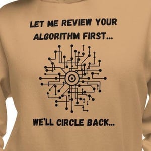 May include: A tan-coloured hoodie featuring black text and a circuit board graphic. The text states "LET ME REVIEW YOUR ALGORITHM FIRST... WE'LL CIRCLE BACK..." The graphic is a stylized circuit board design.