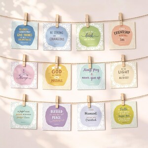 May include: A display of inspirational quote cards, each clipped to a string with wooden clothespins. The cards feature various pastel colors and decorative borders, with phrases like "Rejoice," "Be Strong," and "Faith." The overall theme is motivational and uplifting.