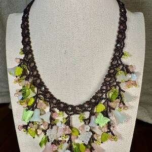 Collana con pietre preziose di grande impatto, caratterizzata da un ramo floreale, perline, quarzo, giada e diaspro