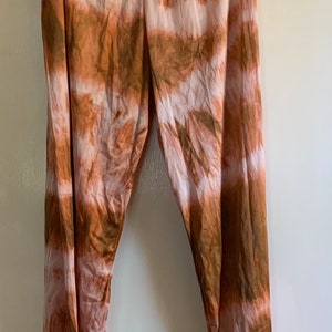 Op de afbeelding: Een broek van bruin en wit tie-dye. De broek heeft een wijde pijp en een ontspannen pasvorm.