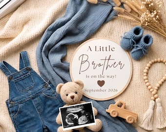 May include: A round wooden sign with the text A Little Brother is on the way! September 2026, a blue denim overall, a crocheted teddy bear holding a baby ultrasound scan, blue knitted booties, a wooden toy car, and a string of wooden beads.