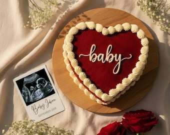 May include: A heart-shaped cake with red frosting and white frosting trim, with the word "baby" in white script. An ultrasound image and two red roses are also present, along with baby's name and the month and year of birth.