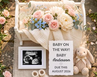 May include: A white wooden cradle filled with a cream muslin cloth and a bouquet of pink roses, white peonies, and blue forget-me-nots. Includes a framed ultrasound, a pair of cream knit booties, a plush bunny, and a sign reading BABY ON THE WAY!