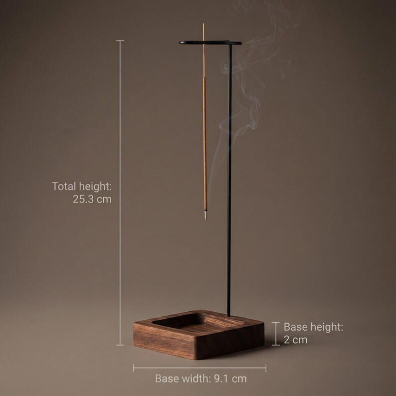 May include: A black metal incense holder with a wooden base. The total height is 10 inches, the base width is 3.6 inches, and the base height is 0.8 inches. An incense stick is lit, with smoke rising. The holder is designed for incense sticks.