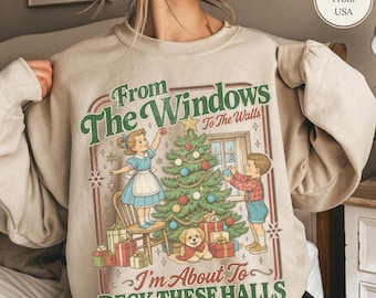 Könnte beinhalten: Ein sandfarbenes Sweatshirt mit Rundhalsausschnitt und einer Vintage-Grafik von zwei Kindern, die einen Weihnachtsbaum schmücken. Der Text lautet, From The Windows To The Walls I'm About To DECK THESE HALLS, mit einem kleinen Hund bei Geschenken.