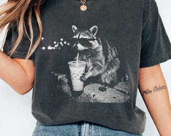 Camiseta unisex con mapache bebiendo café helado, divertida camiseta con meme de animales, ideal para amantes del café.