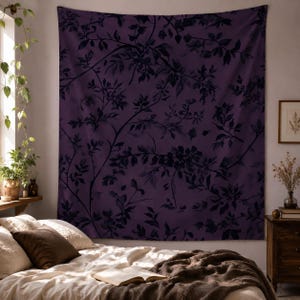 May include: A large rectangular wall tapestry featuring a deep purple background with a dark, monochromatic botanical print of sprawling branches, leaves, and small flowers. The fabric hangs flat against the wall, displaying a repeating pattern.