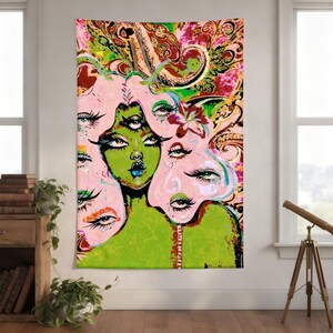 May include: A vibrant tapestry featuring a surreal illustration of a green-skinned figure with multiple eyes and pink hair. The artwork has a paisley and floral background with a bold color palette, creating a psychedelic and artistic aesthetic.