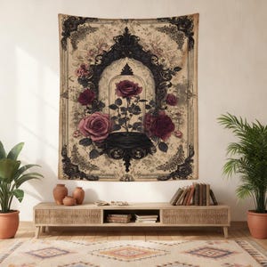 May include: A rectangular wall tapestry featuring a central dark ornate frame enclosing a single red rose inside a glass cloche. The design includes surrounding red roses and foliage set against a beige background with intricate black border details.