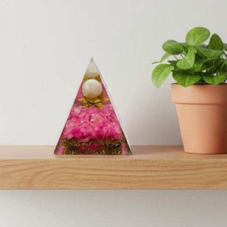 Top-down perspective of the Orgone Pyramid, highlighting the symmetry of the central sphere and the distribution of the Rose Quartz chips. This image emphasizes the pyramid's role in sacred geometry and energy balancing for a peaceful home environment.