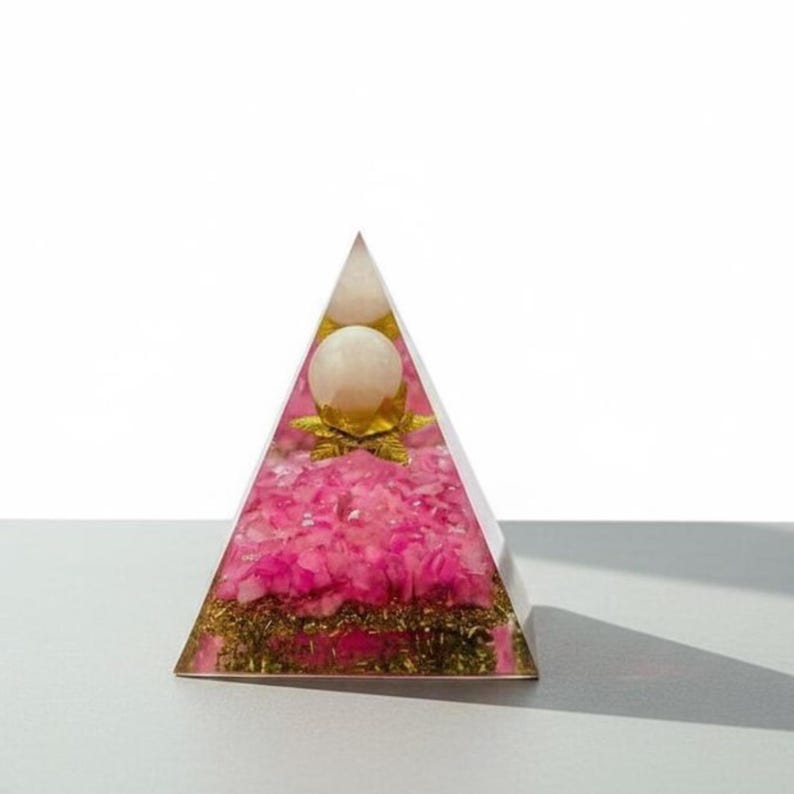 Detailed shot of the golden metal flakes at the base of the Rose Quartz Orgone Pyramid. The metal shavings are essential for the Orgonite's ability to shield against EMF radiation from computers and smartphones in a modern home office.