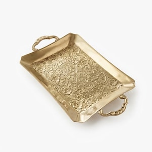 May include: A rectangular brass tray featuring an intricate embossed floral pattern across its base. The tray includes two ornate, curved handles on opposite ends, with a polished metallic finish that reflects light across the textured surface.