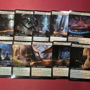 Pode incluir: Uma cole&ccedil;&atilde;o de dez cartas colecion&aacute;veis Magic: The Gathering. Cada carta apresenta obras de arte de fantasia e texto &uacute;nicos, com t&iacute;tulos como "Shadowy Backstreet" e "Underground Mortuary". As cartas est&atilde;o dispostas sobre uma superf&iacute;cie vermelha.