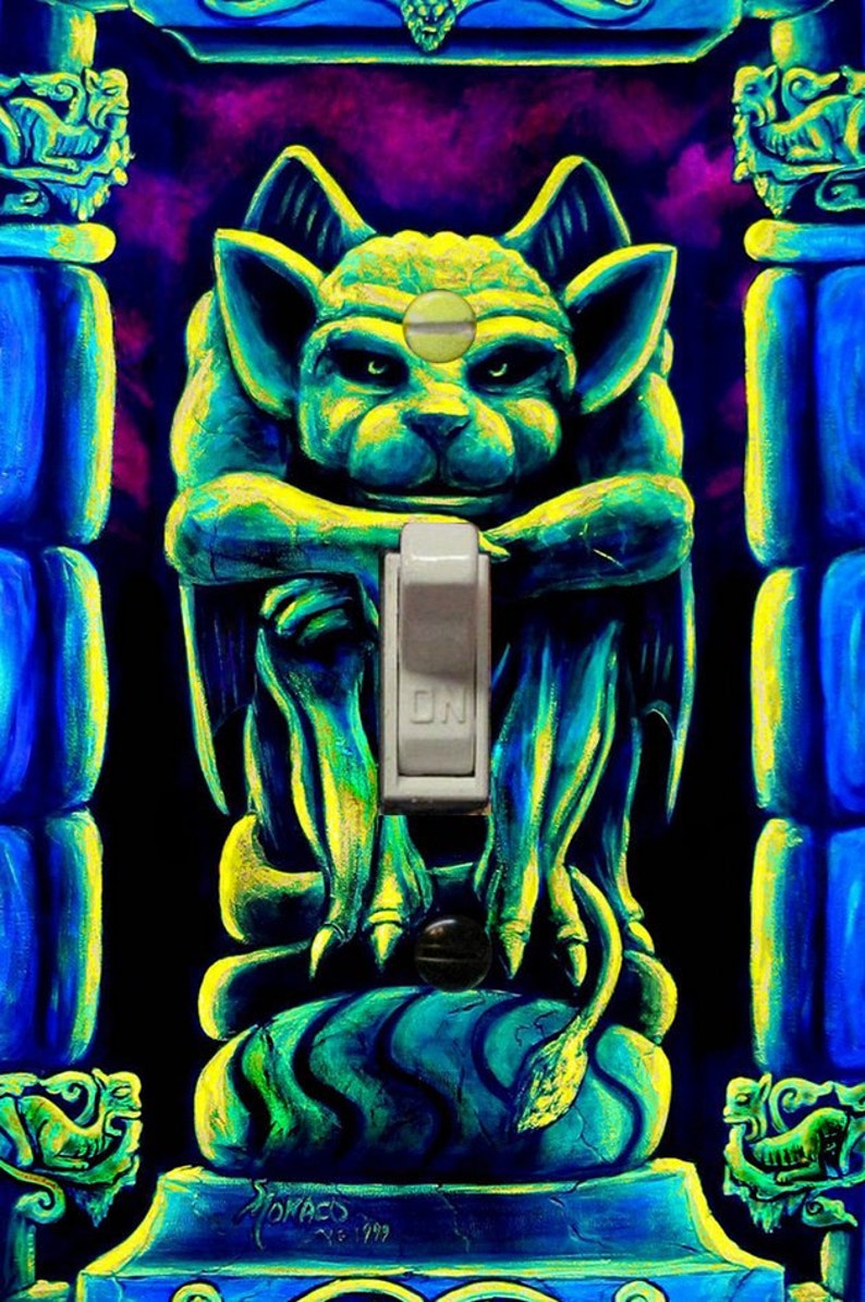 May include: A unique light switch cover featuring a gargoyle design in shades of blue and yellow. The switch is in the 'ON' position. The artwork has a fantasy theme and is set against a dark background.