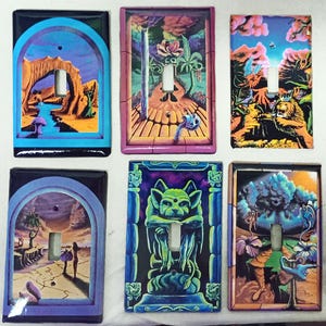 May include: Six decorative light switch covers with colorful, surrealist artwork. Each cover features a unique design, including landscapes, a gargoyle, and fantastical creatures. The covers have a glossy finish and are rectangular with a toggle switch opening.