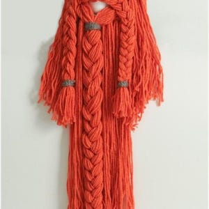 Puede incluir: Un conjunto hecho a mano de sombrero y barba vikingos. El sombrero es gris con dos cuernos color crema. La barba está hecha de hilo naranja, con tres secciones trenzadas y detalles grises. La barba cuelga, creando una pieza de disfraz única.