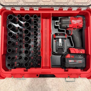 May include: A red Milwaukee tool case with a clear lid, containing a black impact wrench, battery, and a set of black sockets. The sockets are arranged by size, with measurements in inches. The tool case is open and ready for use.