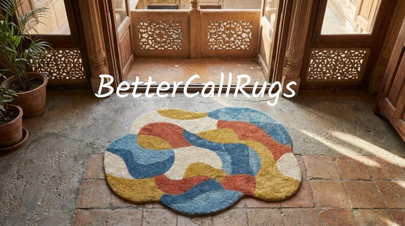 May include: A colorful, abstract rug with a cloud-like shape. The rug features a pattern of blue, yellow, orange, and cream shapes. The text "BetterCallRugs" is displayed above the rug.