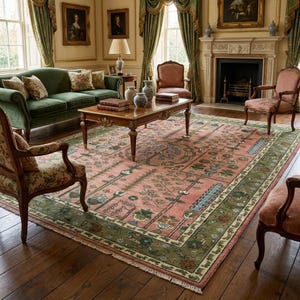 May include: A large rectangular area rug featuring a central medallion and floral motifs in shades of pink, green, and cream. The rug has a wide decorative border with intricate patterns and fringe along the edges, placed on a dark wood floor.
