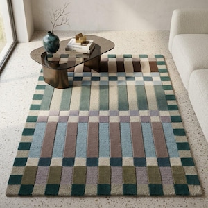 May include: A rectangular area rug featuring a geometric pattern of vertical and horizontal blocks in shades of teal, sage green, light blue, lavender, brown, and cream. The design consists of repeating rectangular segments and a border.
