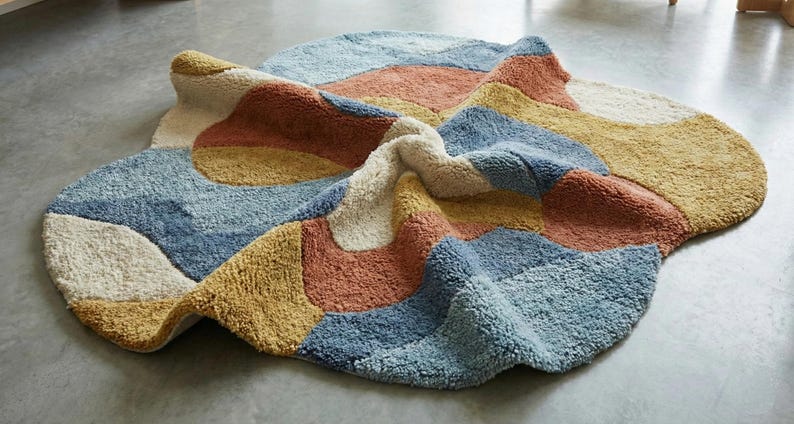 May include: A colorful, abstract rug with a soft, textured surface. The rug features a patchwork design with sections of blue, yellow, orange, and cream. The rug is approximately 60 inches in diameter, perfect for a living room or bedroom.