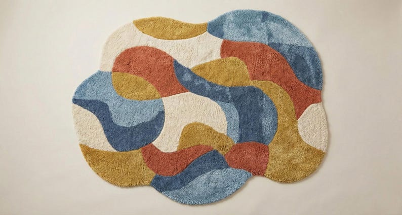 May include: A colorful, abstract rug with a cloud-like shape. The rug features a mix of colors, including blue, orange, yellow, and cream. The rug is made of a soft, textured material, and would be a great addition to any room.