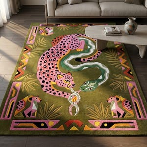 Könnte beinhalten: Ein rechteckiger Teppich mit olivgrünem Hintergrund, der einen großen rosa Leoparden mit schwarzen Flecken und eine geschwungene grüne Schlange zeigt. Das Design umfasst stilisierte Palmblätter, geometrische Ränder in Rosa und Gelb sowie zwei kleine rosa Tierfiguren am unteren Rand.