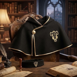 Puede incluir: Una capa negra con capucha, ribete dorado y un cierre de botón dorado. La capa presenta un emblema dorado bordado de un cráneo de toro estilizado en el lado izquierdo. Se incluye una cinta para la cabeza negra a juego con el mismo emblema.
