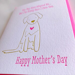 May include: A white card with a gold outline of a dog with a pink heart on its chest. The text on the card reads "You may have adopted me... But I'm pretty sure I own you." and "Happy Mother's Day".