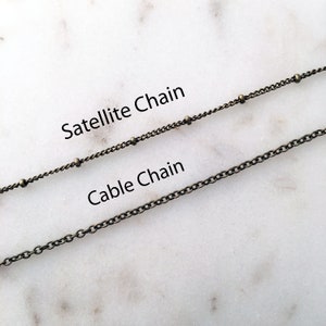 May include: Two types of chain, a cable chain and a satellite chain, are shown on a white marble surface. The text "Cable Chain" and "Satellite Chain" is written below each chain.