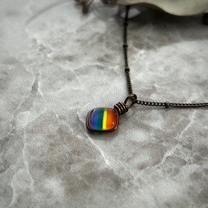 An angled side view of the tiny rainbow necklace.