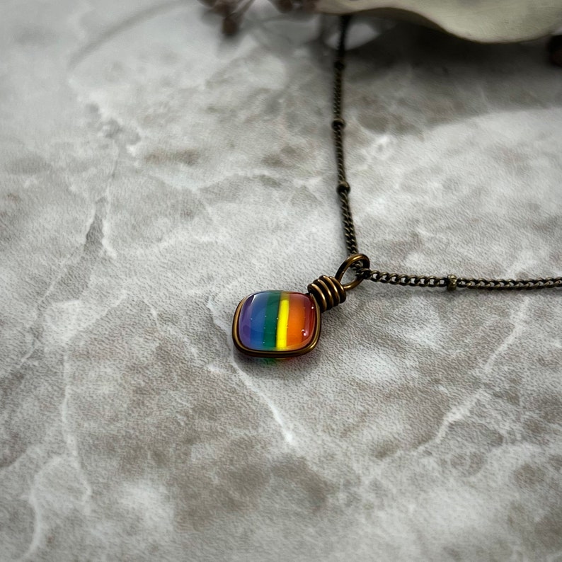 An angled side view of the tiny rainbow necklace.