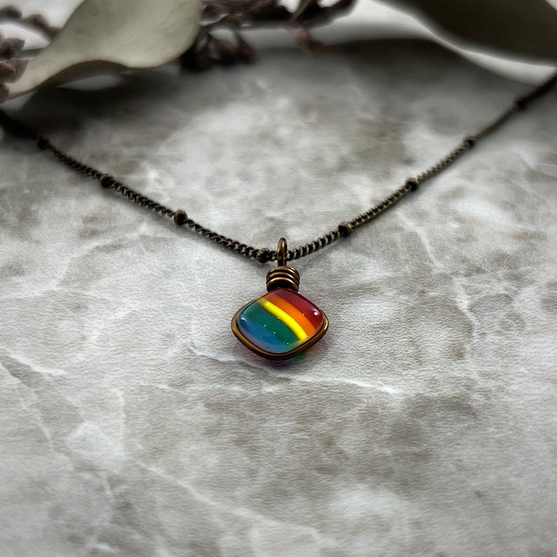 An angled front view of the tiny rainbow necklace showcasing the pendant's depth.