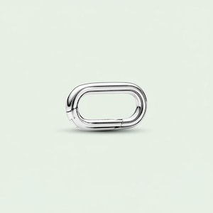 May include: A shiny, silver-colored oval link clasp. The clasp is made of a smooth, polished metal and has a hinged opening. The design is simple and modern, with a focus on clean lines and a minimalist aesthetic. The clasp is likely used for jewelry or accessories.
