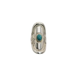 Puede incluir: Anillo plateado con una piedra turquesa ovalada en el centro. El anillo tiene un diseño alargado con patrones decorativos y un acabado pulido. La piedra turquesa es de un color azul-verdoso vibrante.