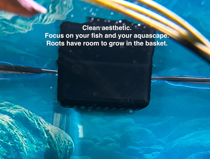 May include: A black square aquarium basket submerged in blue water. The text "Clean aesthetic. Focus on your fish and your aquascape. Roots have room to grow in the basket." is visible.