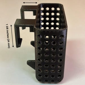 May include: Black, 3D-printed aquarium accessory with a rectangular perforated container and mounting brackets. The container is 1 inch (25 mm) wide and 1 3/8 inches (34 mm) tall. Text at the bottom reads "29 gallon & 20 gallon long".