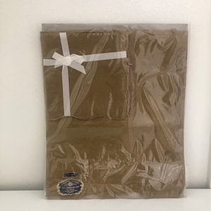 May include: A brown linen tablecloth with a white ribbon tied in a bow. The tablecloth is packaged in clear plastic and has a label that reads "18 Inch Luncheon Set - Made in England".