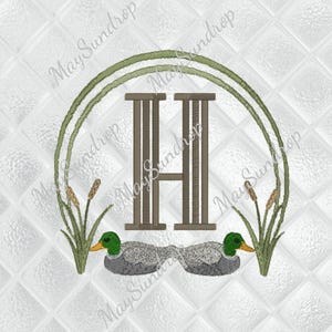 May include: Embroidered design featuring the letter "H" in a brown, vertical, striped font, framed by a green arch and cattails. Two ducks with green heads and gray bodies are at the bottom. The background is a white, quilted pattern.
