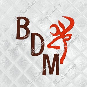 May include: Embroidered design featuring the letters "BDM" in a dark brown color, accompanied by a stylized orange deer head logo. The design is set against a white, textured background with a quilted pattern.
