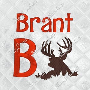 Könnte beinhalten: Ein gesticktes Design mit dem Namen "Brant" in Rot, über einem großen roten Buchstaben "B" und einer braunen Silhouette eines Hirsches mit Geweih. Das Design befindet sich auf einem weißen, gesteppten Hintergrund.